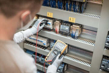 Electricians hands testing current electric in control panel