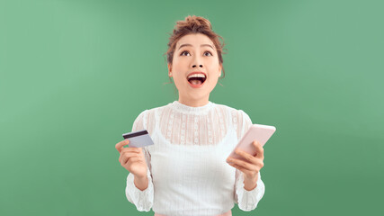 Smiling girl holding phone and credit card. Shopping online concept.