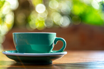 relax time, cup of coffee with green and yellow blured bokeh background outdoor on wood in morning sun light