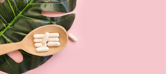 wooden spoon, collagen capsules on colored background