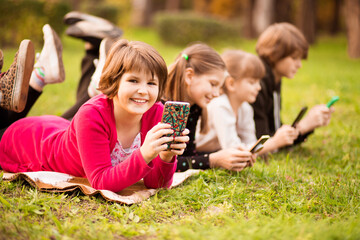 Outdoor portrait of little girls and boys playing with phones . High quality photo