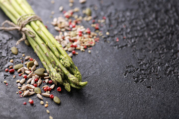 Fresh green vegetables. Raw asparagus with spices on a black table. Background image, copy space, horizontal, rustic