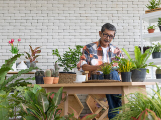 A goold looking senior Asian man wearing eyesglasses sitting and drink coffee and reading the newspaper with happiness. Idea for relaxing and slowly life of older people after retirement