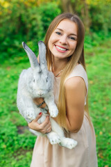Farmer holding white rabbit in spring garden. rabbit sitting in woman's hands.