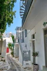 Beautiful traditional narrow cobbled streets of Greek island towns. Whitewashed houses, flower pots, balconies, stairs and doors. Mykonos, Greece