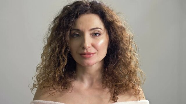 Portrait of a charming, well-groomed middle-aged woman with brown curly hair.