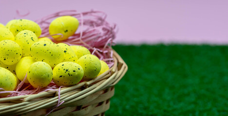 Yellow Easter Egg with freckles pattern inside a basket on top of grass