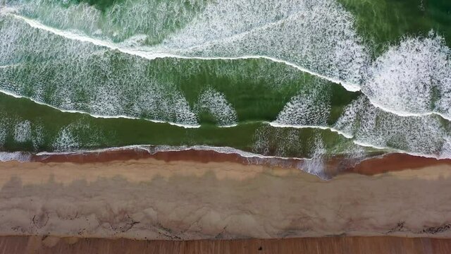 Aerial panning shot of waves splashing on shore at beach, drone flying over coastline - Cape Cod, Massachusetts