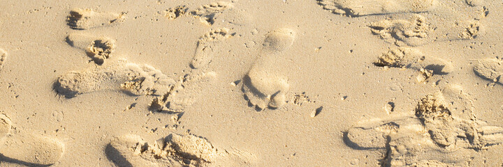 many footprints of people on the sand of the beach. Banner.