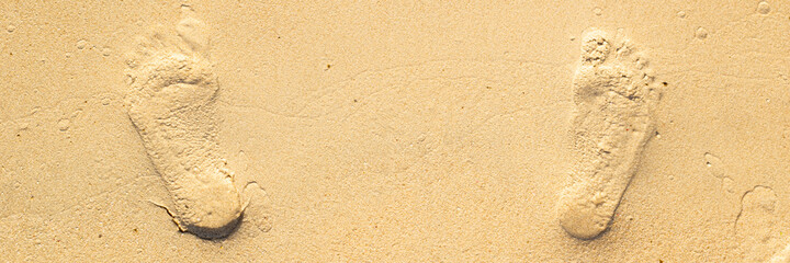 footprints from two feet on the sand of the beach. Top view. Banner.