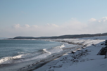 the seashore in the snow. Blue waves on the blue sea. Sea shore. Sand. 