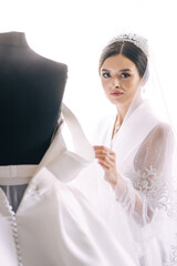beautiful bride smiles near a mannequin with a wedding dress. We
