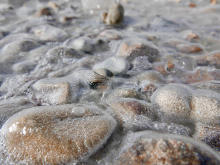 sea stones under thin cover of ice crust. close up view.