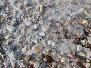 pebble stones under thin cover of ice crust