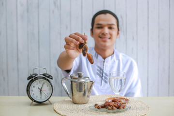 Dates on muslim man hands with clock showing 6 o'clock for iftar time