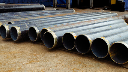 Raw Pipes Material Black Steel Laying on the Ground 