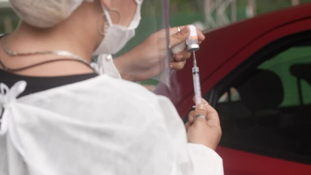 Nurse at immunization campaign is Making a Vaccine Injection to a elderely. Needle and a Syringe at corona virus vaccination campaign 

