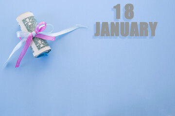 calendar date on blue background with rolled up dollar bills pinned by blue and pink ribbon with...