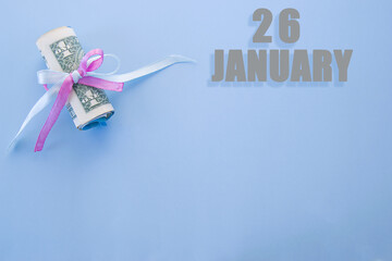 calendar date on blue background with rolled up dollar bills pinned by blue and pink ribbon with copy space. January 26 is the twenty-sixth day of the month