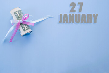 calendar date on blue background with rolled up dollar bills pinned by blue and pink ribbon with copy space. January 27 is the twenty-seventh day of the month