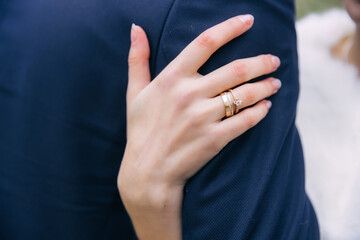 Obraz na płótnie Canvas the bride's hand in wedding rings hugs the groom's shoulders.wedding concept.