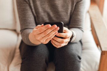 Woman in home clothes with phone in her hand prints message.