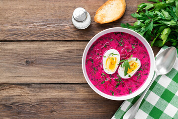 Traditional cold summer beetroot soup with vegetables and boiled egg in a white bowl on wooden table. top view, space for text - 418512072