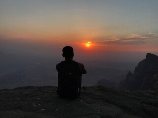 silhouette of a man sitting on a top of mountain