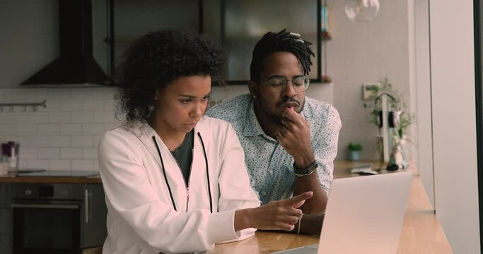 Happy young african mixed race family couple looking at computer screen, amazed by reading email with good news, finding good sale profitable shopping deal, feeling excited giving high five at home.