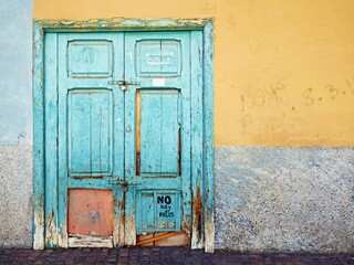 Fototapeta na wymiar A very old coffered wooden door painted with turquoise paint