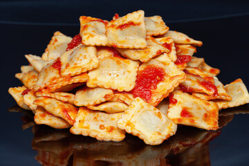 Ravioli with tomato sauce on a dark background