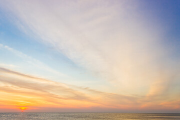 Sunset sky over sea in the evening on sundown with orange sunlight clouds background 