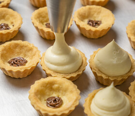Piping cheese tarts fillings. Selective focus.
