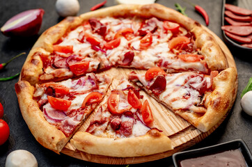 pizza with sausages, mushrooms, tomatoes and cheese on a stone background