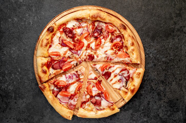 pizza with sausages, mushrooms, tomatoes and cheese on a stone background