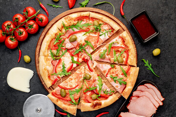 pizza with ham, tomatoes, cheese on a stone background