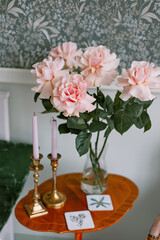 Beautiful bouquet of French roses on a table in a Scandinavian style bedroom with candles