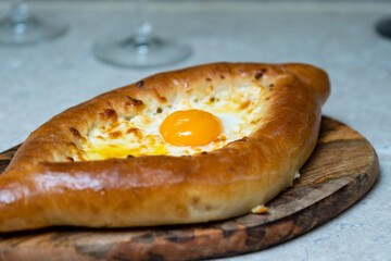 Khachapuri with egg on a wooden tray with wine and tomatoes