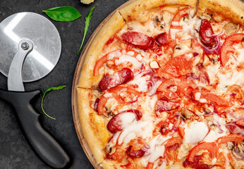 pizza with sausages, mushrooms, tomatoes and cheese on a stone background