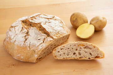 Frisch gebackenes Kartoffelbrot mit Kartoffeln auf Ahorntisch