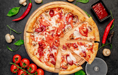 pizza with sausages, mushrooms, tomatoes and cheese on a stone background