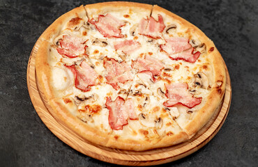 pizza with bacon, mushrooms and cheese on a stone background