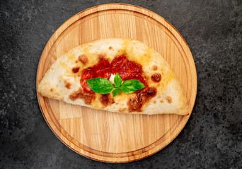 Calzone with ham and mushrooms on a stone background