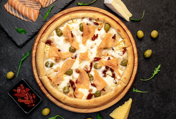 pizza with salmon, cheese and olives on a stone background