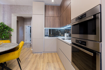 Interior of a stylish modern kitchen in pastel colors, gray, with an insert of black marble