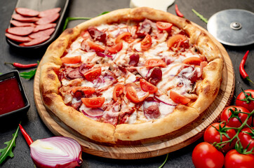 pizza with sausages, mushrooms, tomatoes and cheese on a stone background