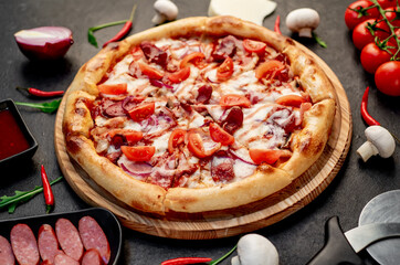 pizza with sausages, mushrooms, tomatoes and cheese on a stone background