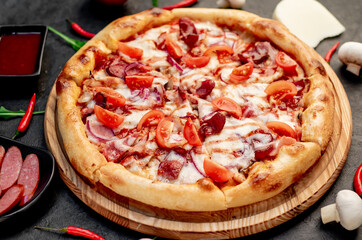 pizza with sausages, mushrooms, tomatoes and cheese on a stone background