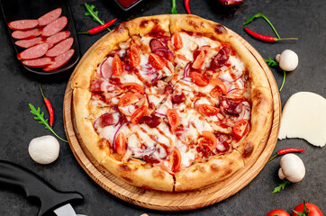 pizza with sausages, mushrooms, tomatoes and cheese on a stone background