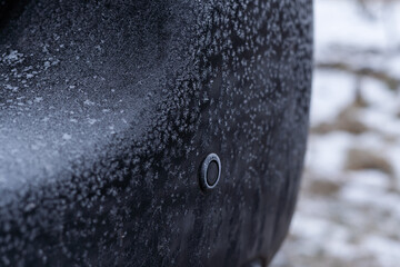 The reverse parking sensor in the car is covered with frost in the morning of winter